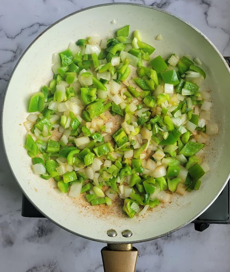 skillet with diced green bell peppers and white onions
