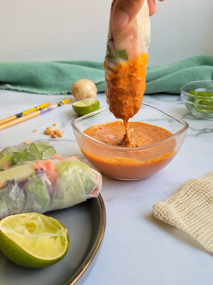 fresh spring roll dipping into peanut sauce