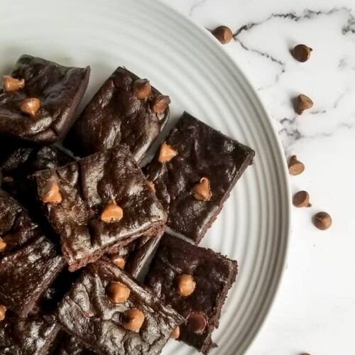 plate of avocado brownies topped with chocolate chips, scattered chocolate chips on the side