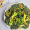 bowl of roasted broccoli with chopsticks in the background