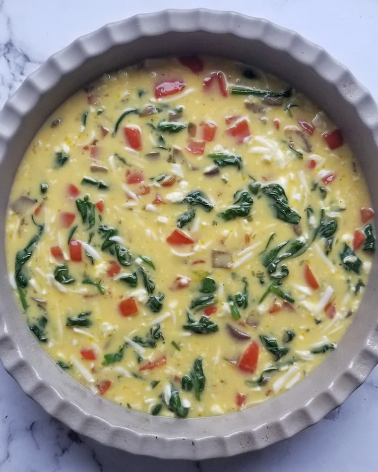 unbaked crustless quiche with veggies in a pie dish