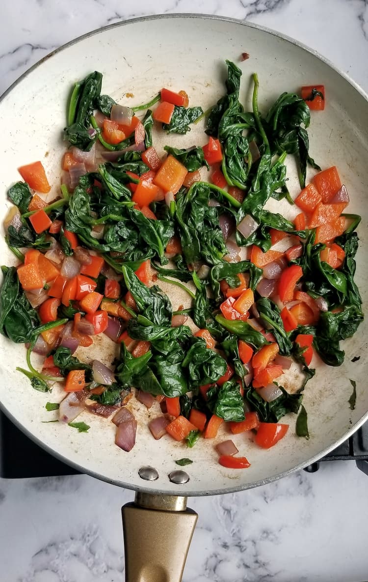 skillet with sautéed red onions, red peppers and spinach