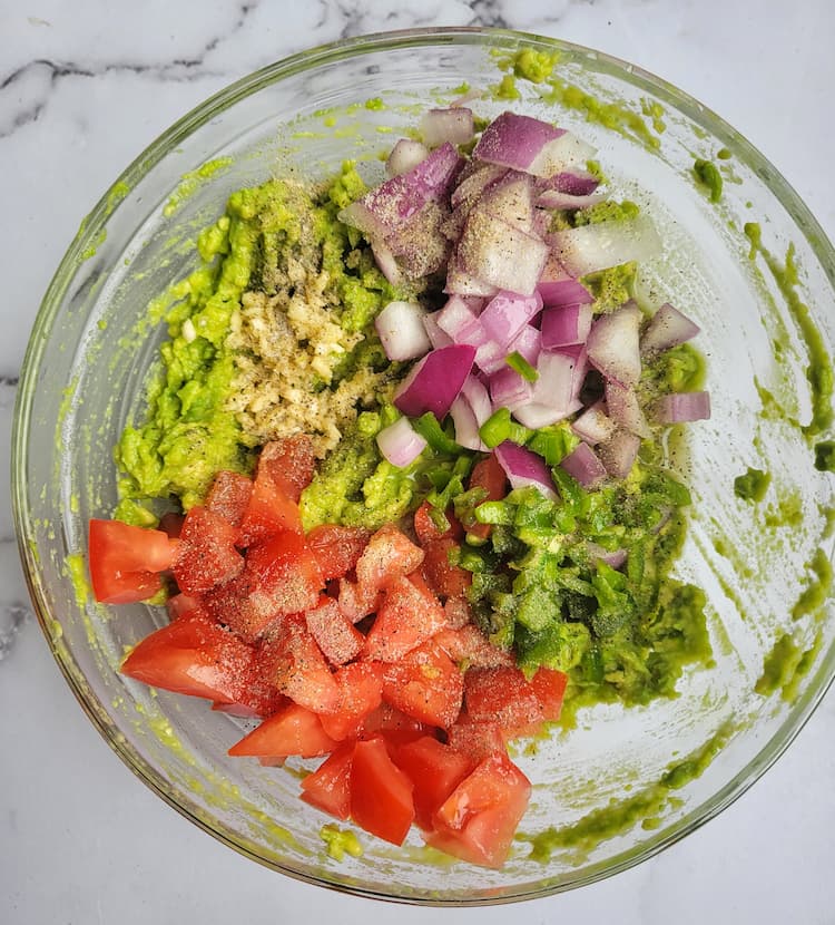 bowl of smashed avocado, diced red onion and tomatoes, minced garlic, salt and pepper