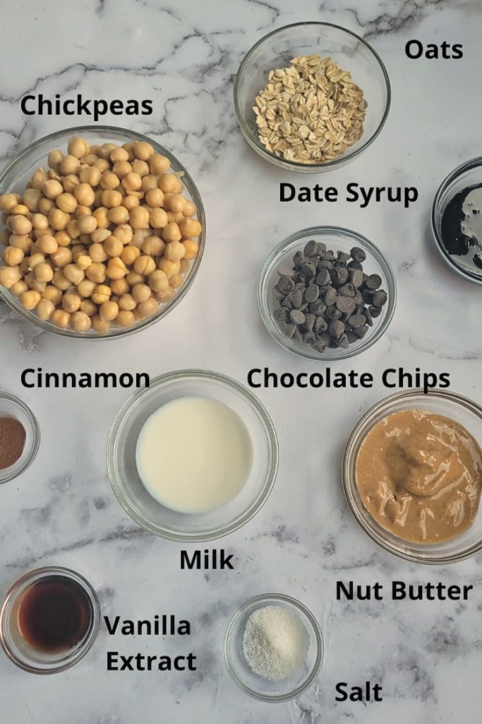 ingredients for cookie dough with chickpeas - chickpeas, oats, date syrup, chocolate chips, milk, salt, nut butter, cinnamon, vanilla extract