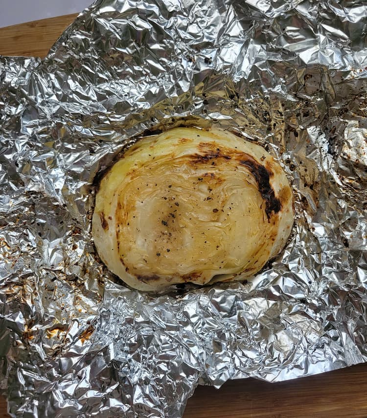 cooked cabbage steak with charred outer edges in an open piece of aluminum foil