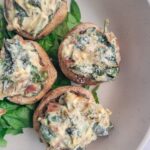 close up shot of 4 creamy stuffed mushrooms with spinach and bacon