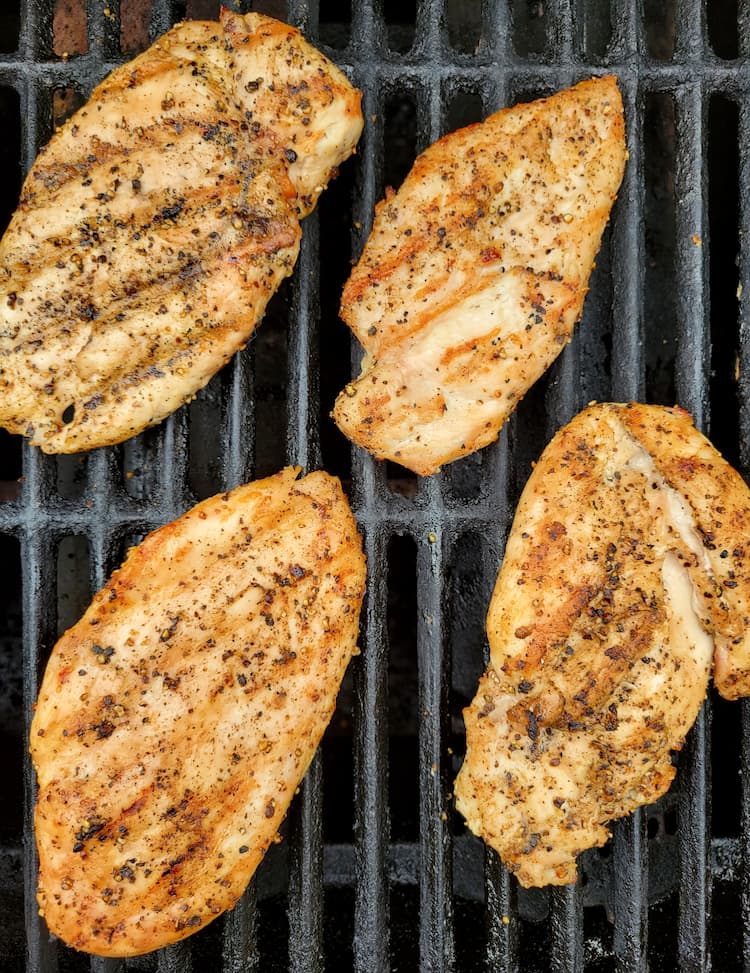 4 cooked chicken breasts on a grill
