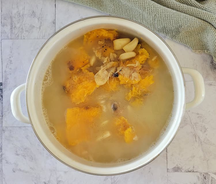 pot with chicken broth, butternut squash and garlic cloves