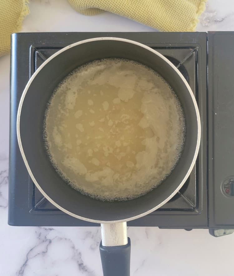 small pot of chicken broth on a burner