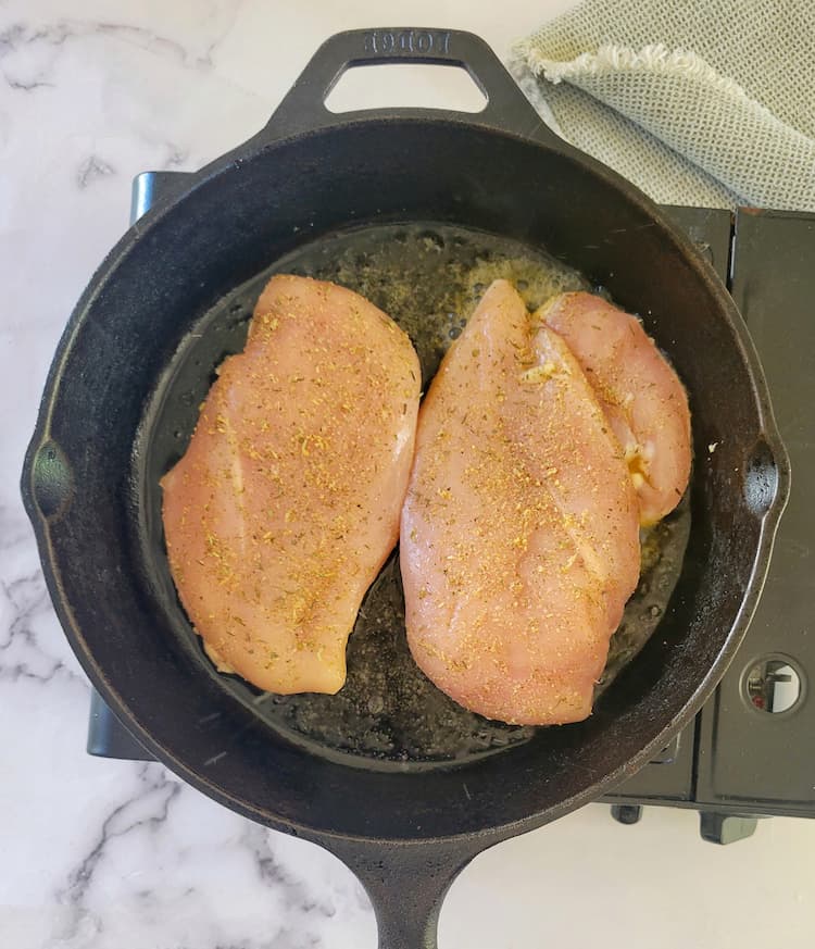 cast iron skillet with 2 seasoned chicken breasts