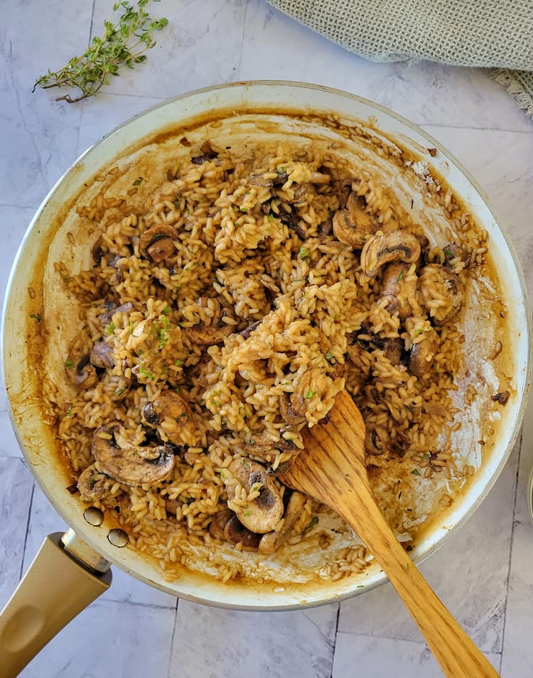 skillet with mushroom risotto and a wooden spatula