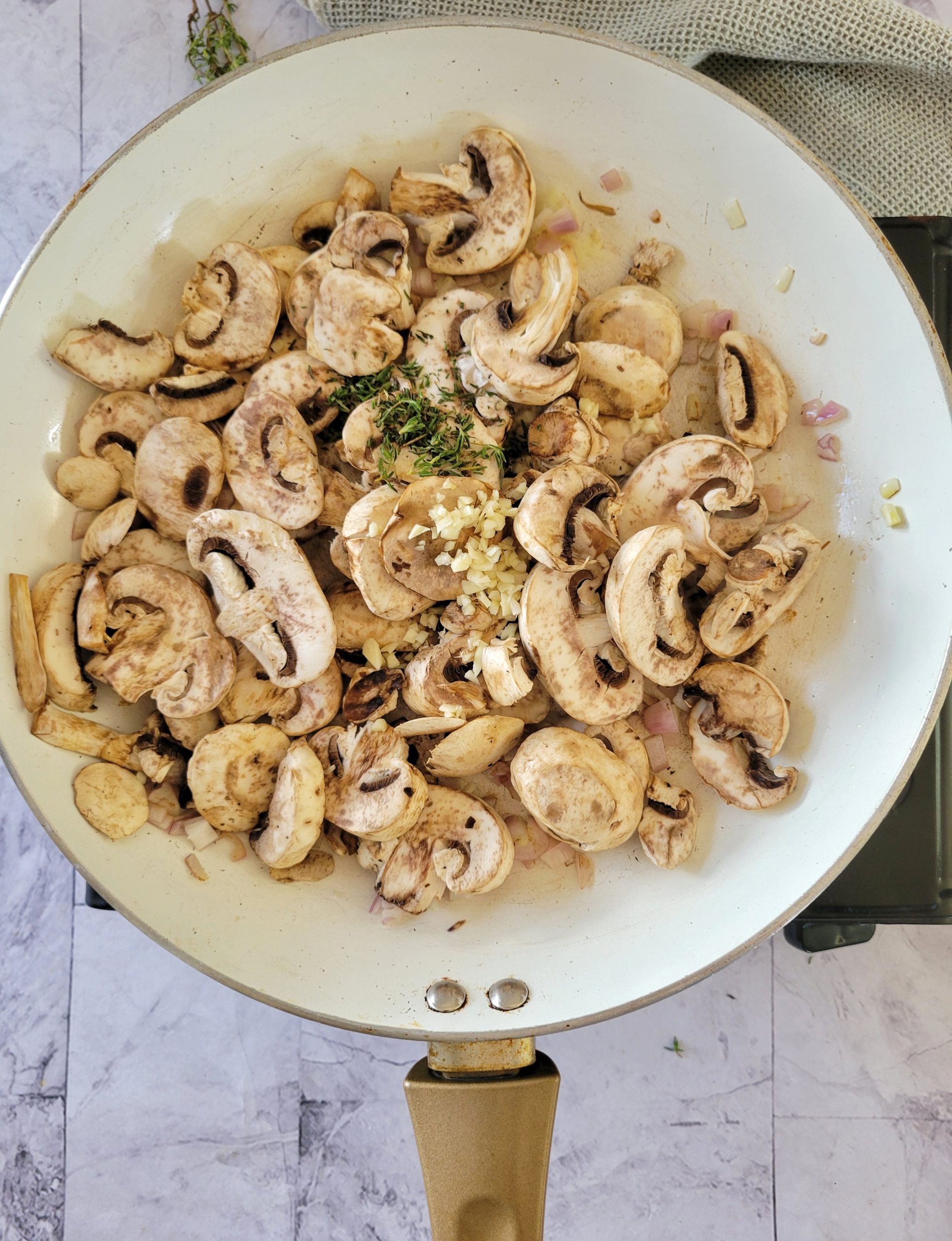 skillet with sliced mushrooms, minced garlic, shallots and herbs