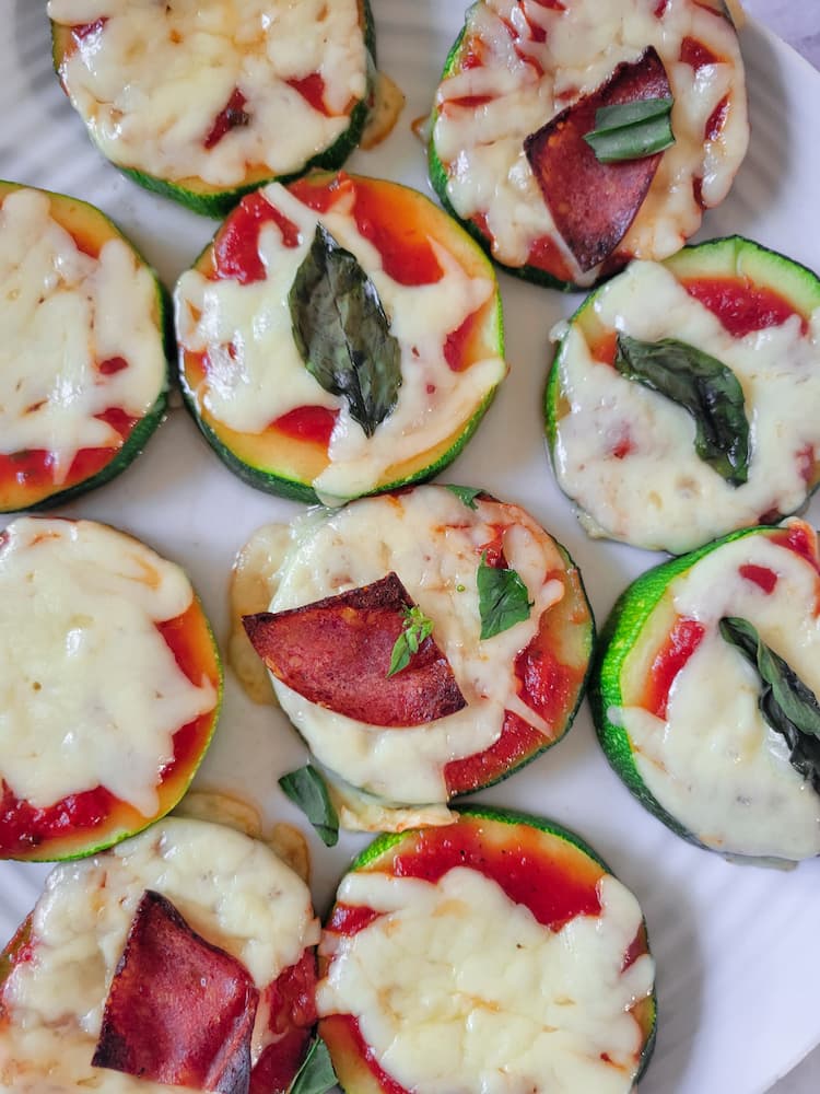 zucchini pizza bites with melted mozzarella cheese and tomato sauce, topped with basil and pepperoni slices