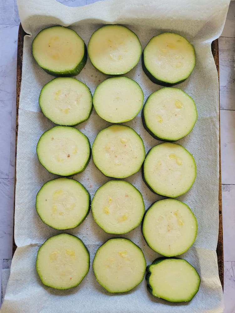 parchment lined baking sheet with raw zucchini rounds