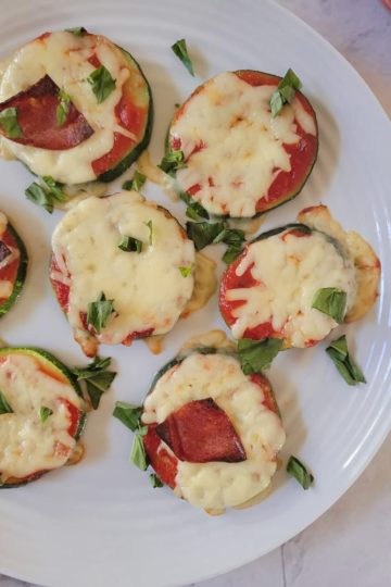 plate with zucchini pizza bites with mozzarella cheese, fresh basil and pepperoni
