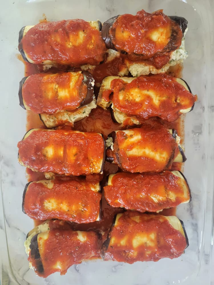 glass baking dish with eggplant rollatini covered in tomato sauce