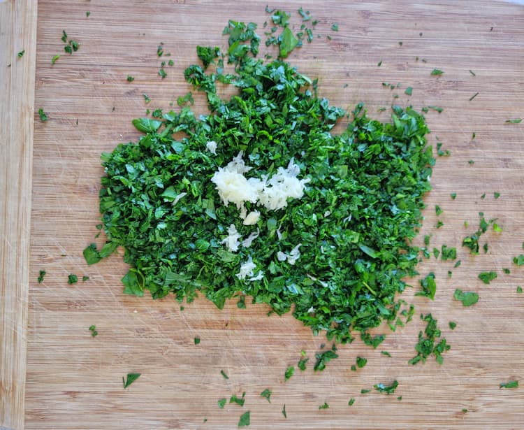 fresh chopped parsley on a cutting board with grated garlic on top