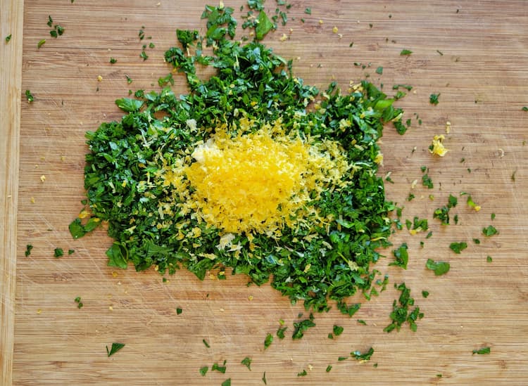 cutting board with chopped parsley, minced garlic and lemon zest