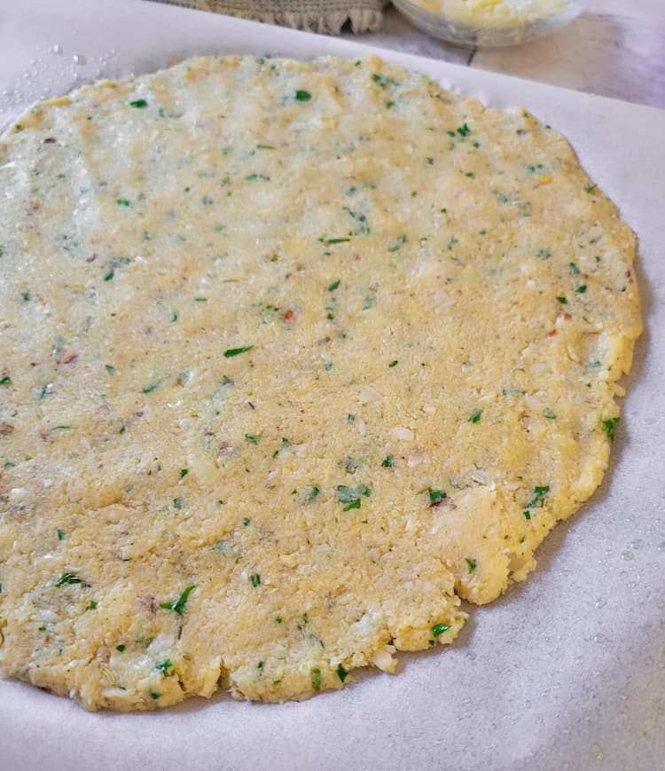 side view of baked untopped cauliflower crust pizza with herbs and spices