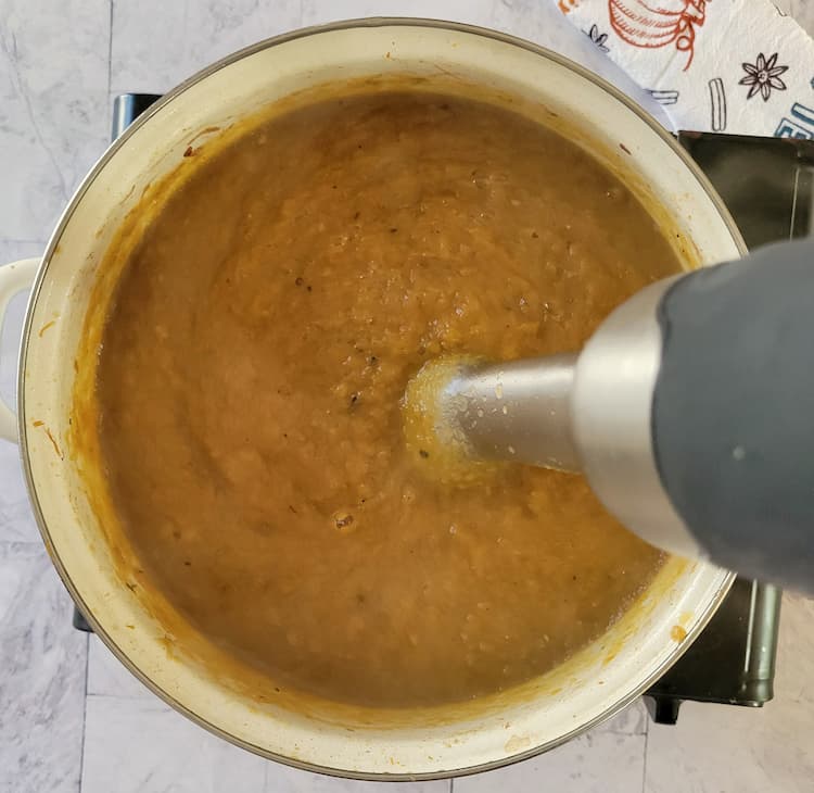 an immersion blender in a pot of pumpkin puree