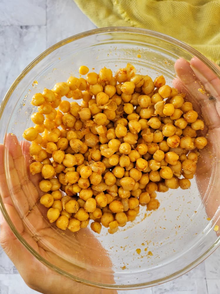 hand holding a bowl of seasoned cooked chickpeas