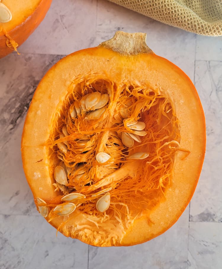half of a cut open pumpkin exposing the flesh and seeds