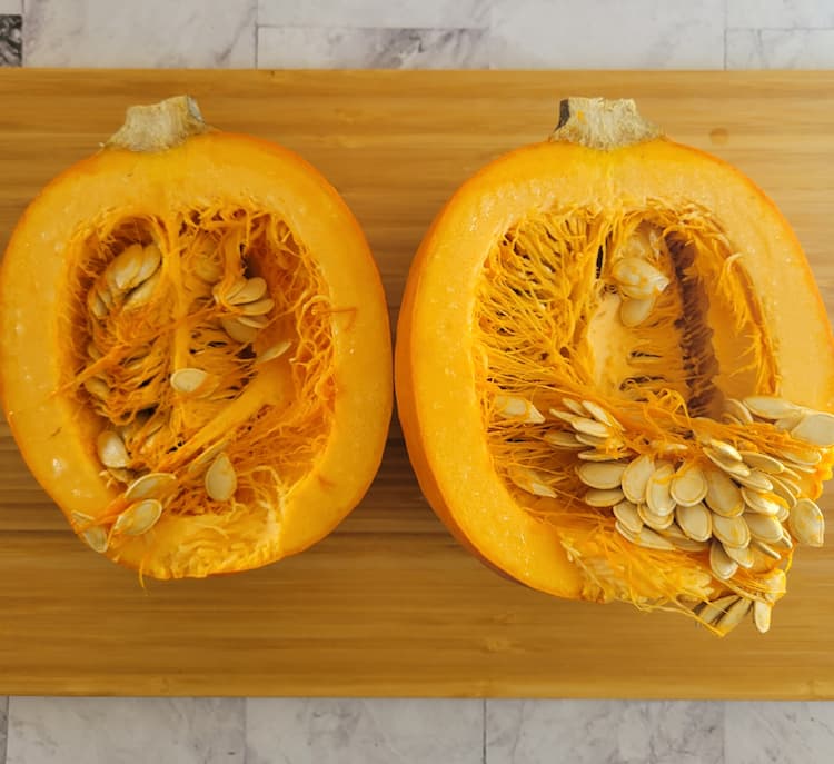 halved and split open sugar pie pumpkin exposing the flesh and seeds