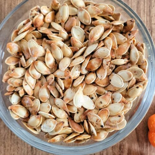 close up of a bowl of whole roasted pumpkin seeds