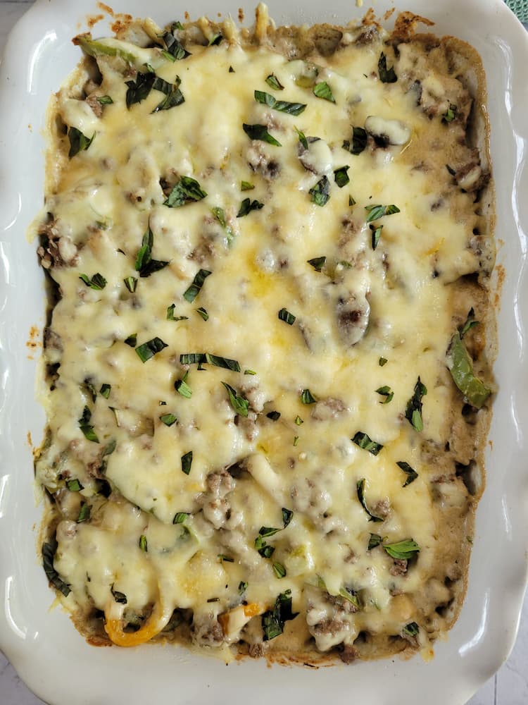 casserole with ground beef, bell peppers and melted mozzarella cheese, fresh basil on top for garnish
