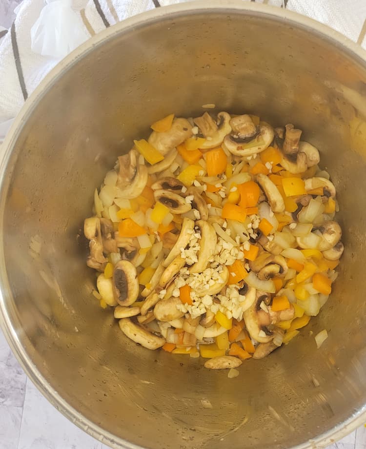 pot of diced white onion, yellow and orange bell peppers, sliced mushrooms and minced garlic