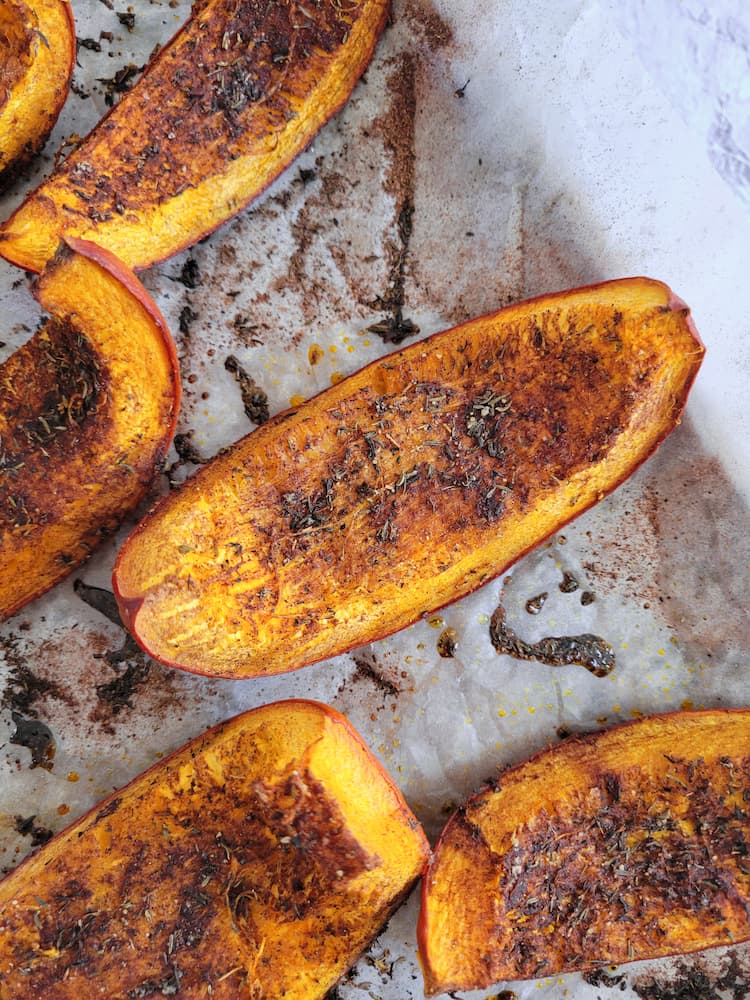 roasted pumpkin wedges on a parchment lined baking sheet