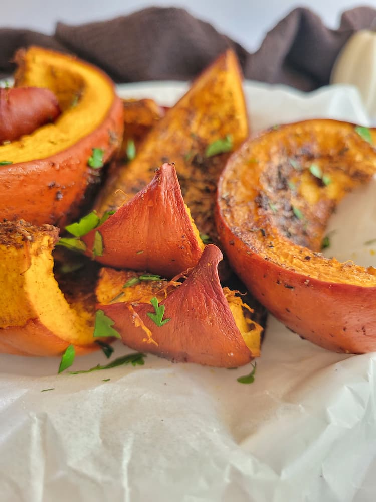 side view of roasted pumpkin wedges garnished with fresh chopped cilantro