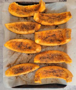 parchment lined baking sheet with seasoned pumpkin wedges