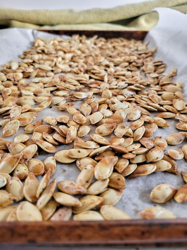 side view of roasted pumpkin seeds on a sheet pan