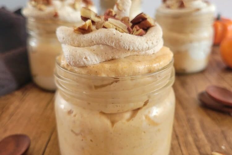 4 jars of pumpkin mousse topped with pecans and whipped cream