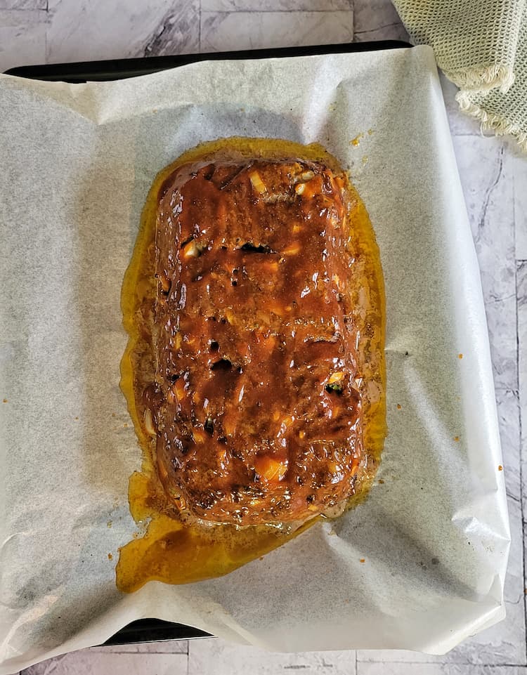 BBQ sauce glazed meatloaf on a parchment lined baking sheet