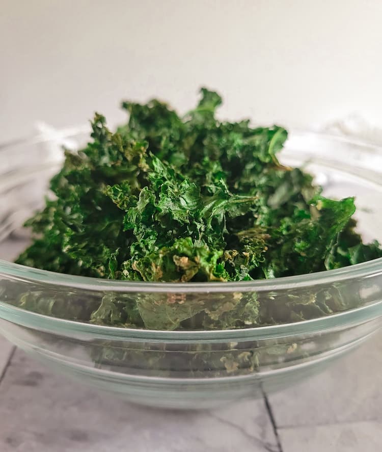 a pile of crispy seasoned kale chips in a glass bowl
