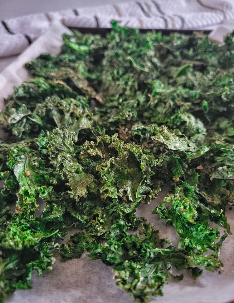 parchment lined baking sheet with crispy seasoned kale chips