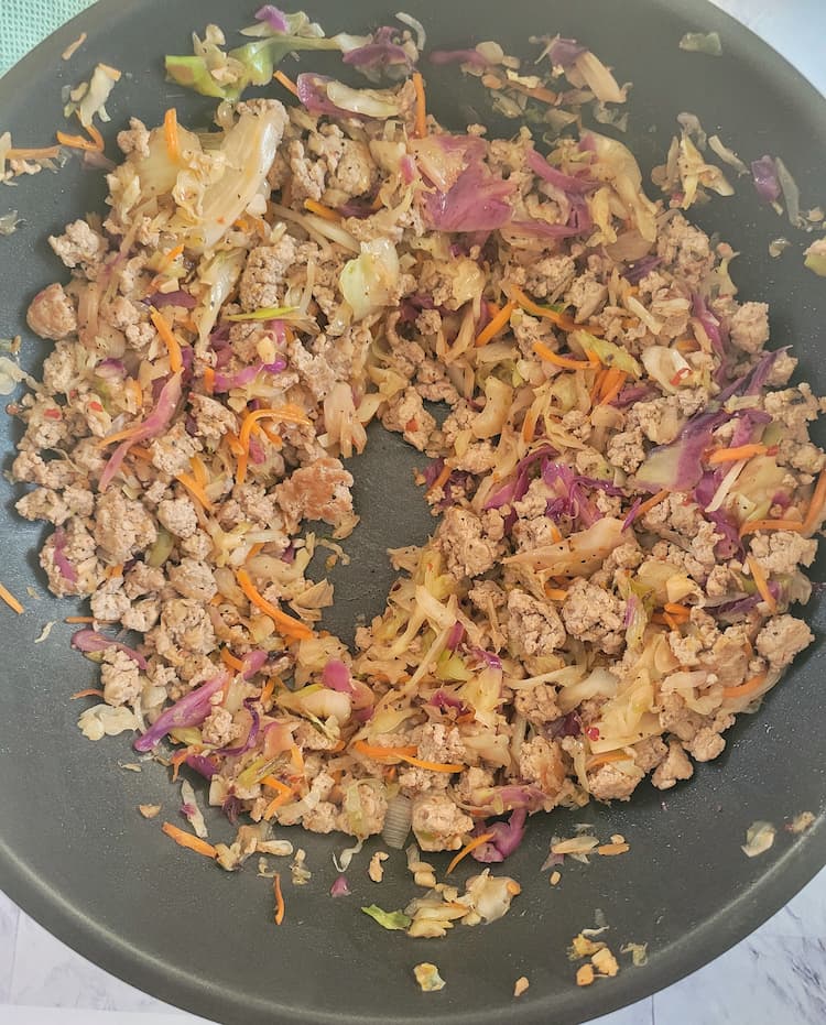 skillet with cooked ground beef and cabbage with a well (hole) in the middle