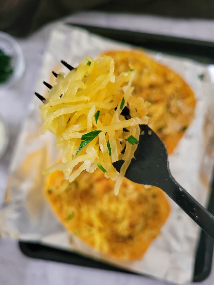 fork full of spaghetti squash garnished with chopped parsley