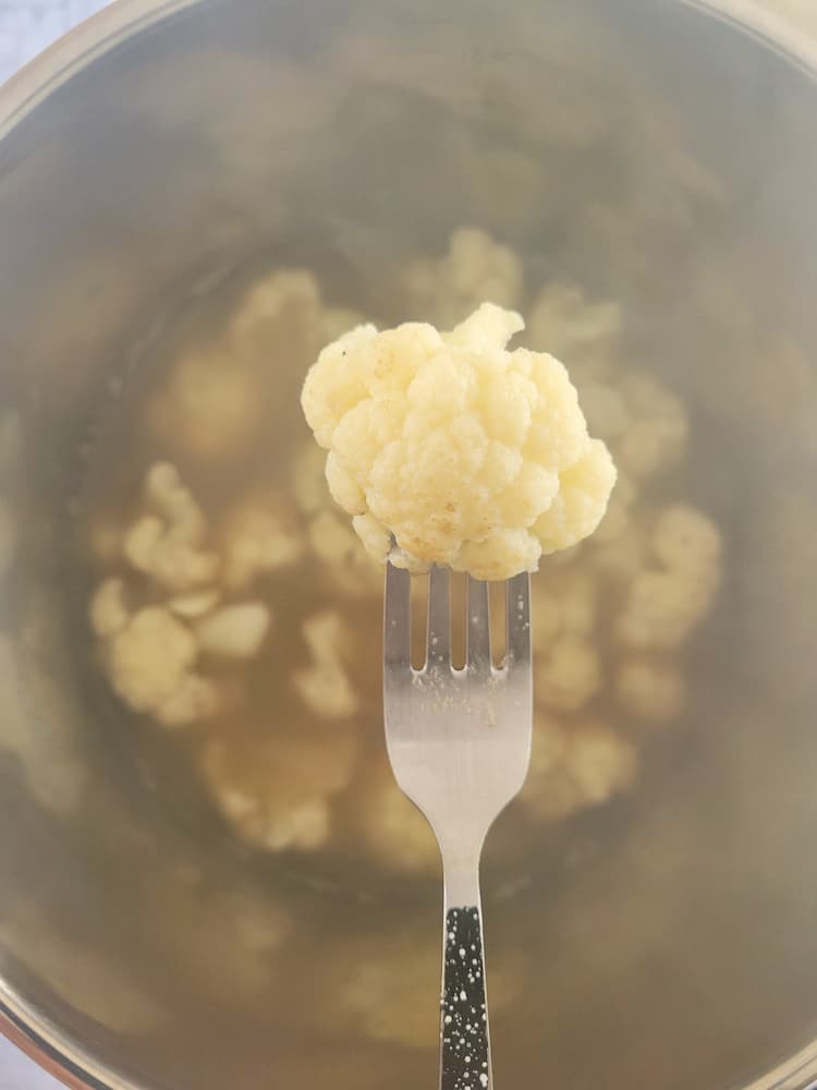 fork with a piece of cauliflower on it over a pot of the rest
