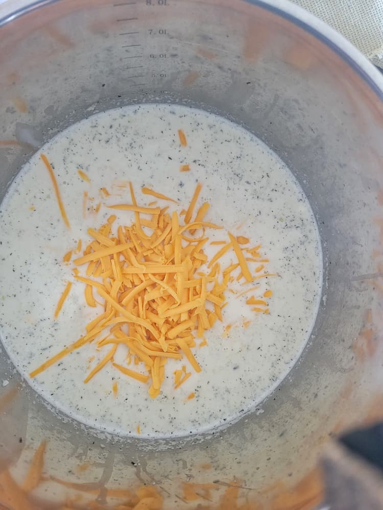 pot of cauliflower soup with grated cheddar cheese on top