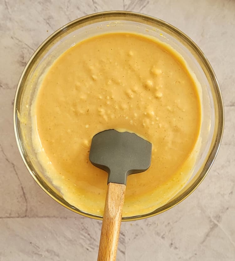 bowl of creamy orange sauce with a mini rubber spatula inside