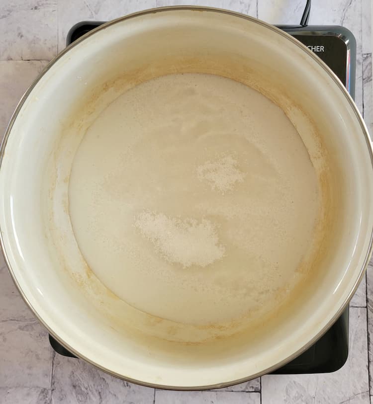 pot with a milky coloured substance and a heaping tablespoon of flour