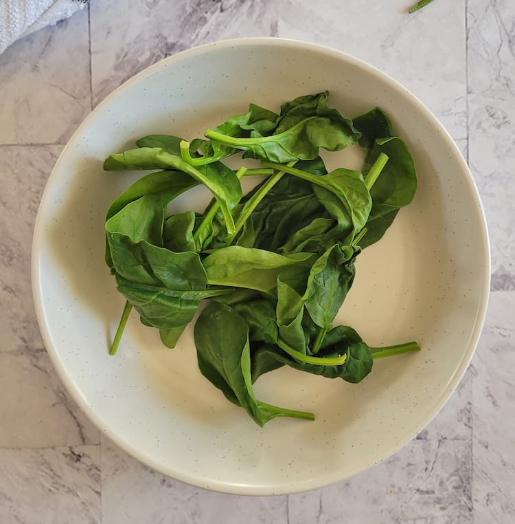 bowl with a handful of fresh raw spinach