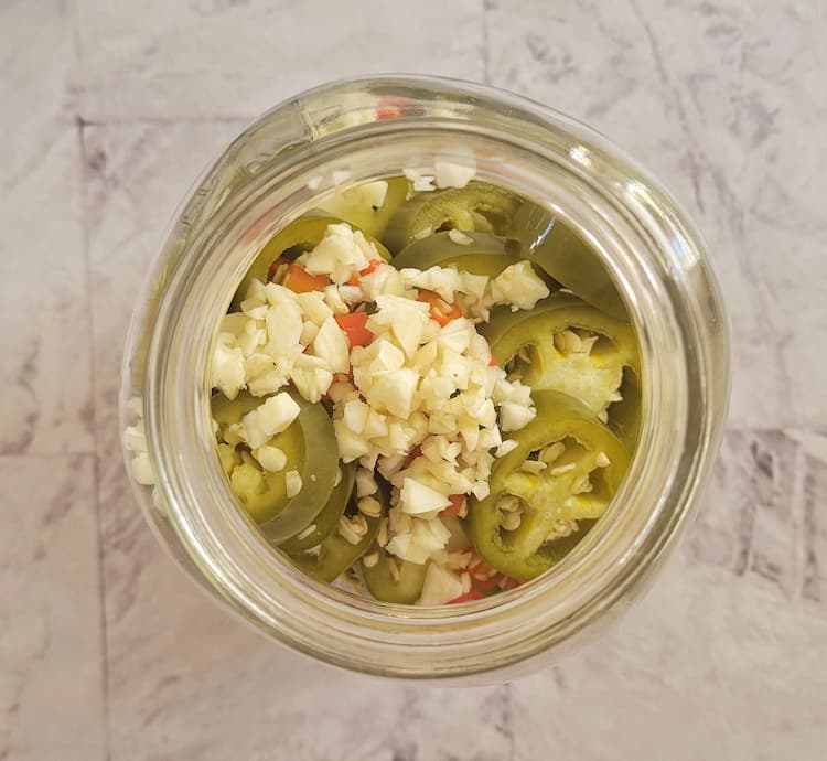 minced garlic in a jar with sliced jalapeños and thai red chilies