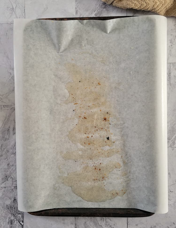parchment lined baking sheet with bacon grease on it