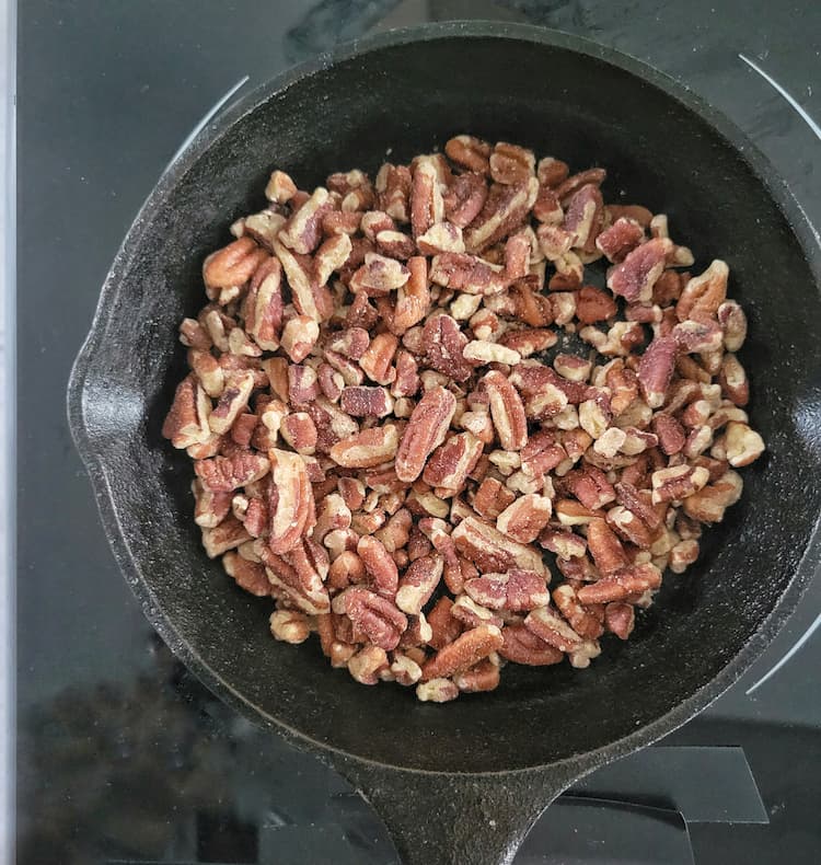 small cast iron skillet with halved pecans in it