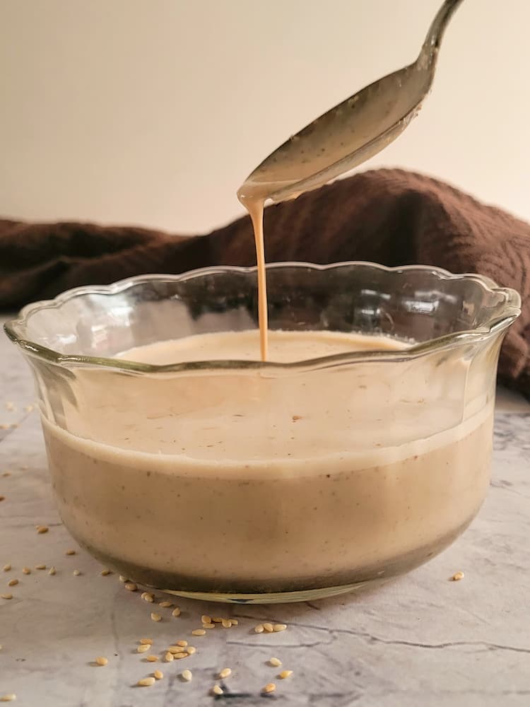 bowl of creamy sauce with a spoon drizzling some down