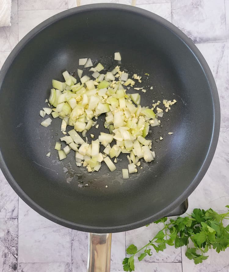 wok with diced white onion and minced garlic